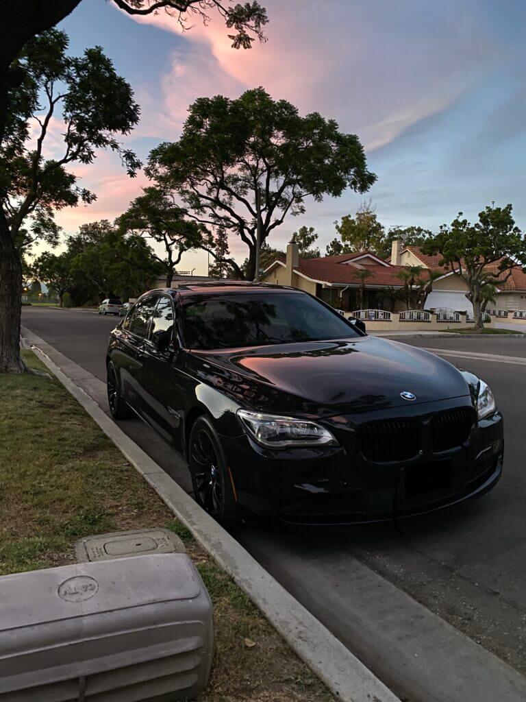 Black BMW sedan parked in a residential driveway after an exterior detail