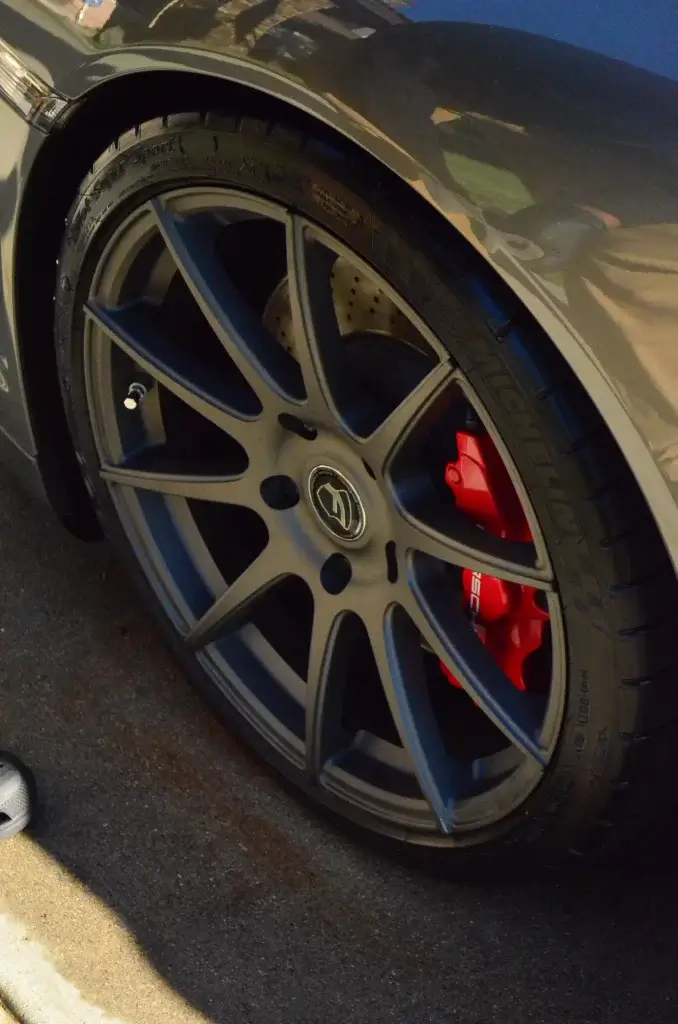Bronze Porsche wheel with red brake calipers cleaned by hand