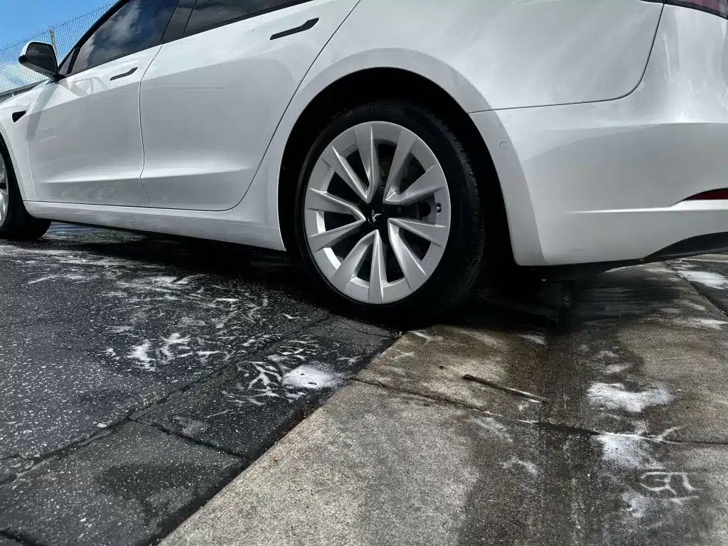White Tesla sedan clean and drying in a driveway after a full detail