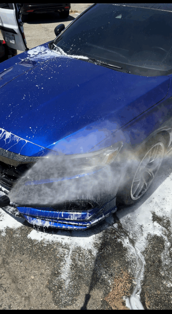 Blue coupe being rinsed after a decontamination wash