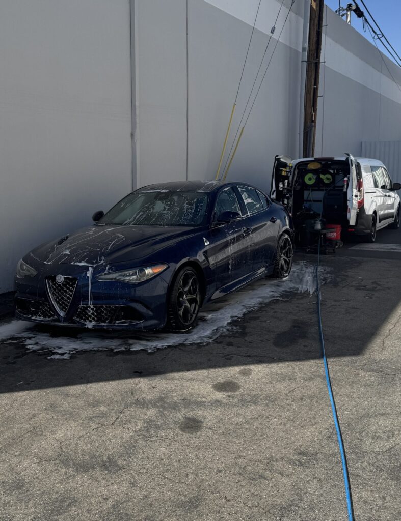 Dark blue sport sedan being washed next to the Automotive Aptitude van