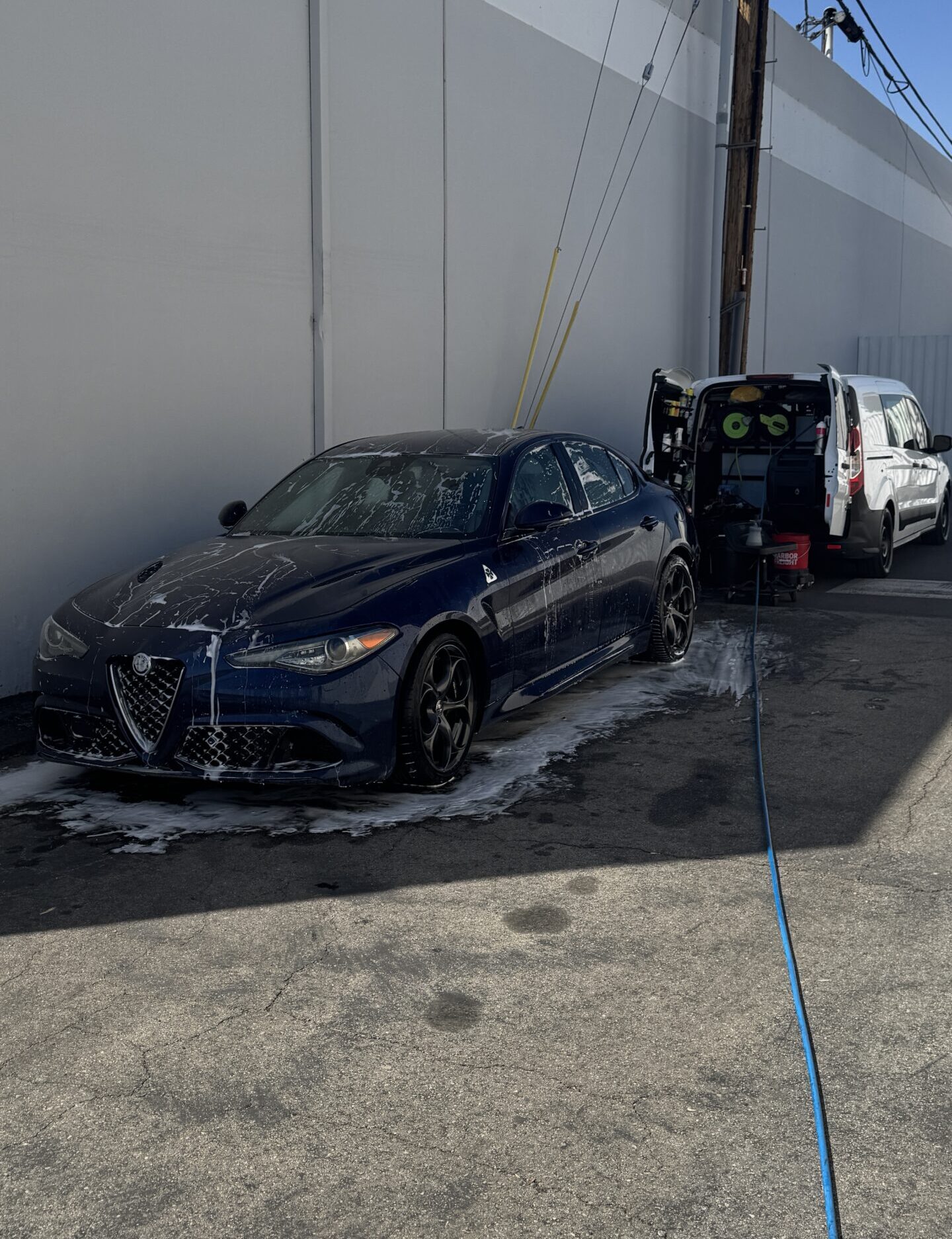Dark blue sport sedan being washed next to the Automotive Aptitude van