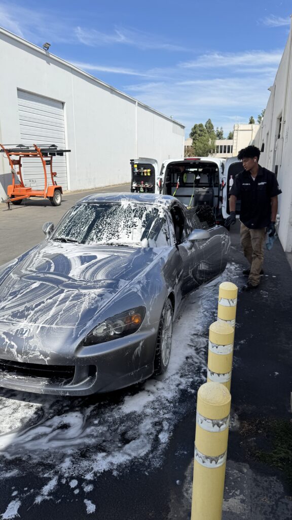 Silver sedan covered in wash foam during a mobile detail