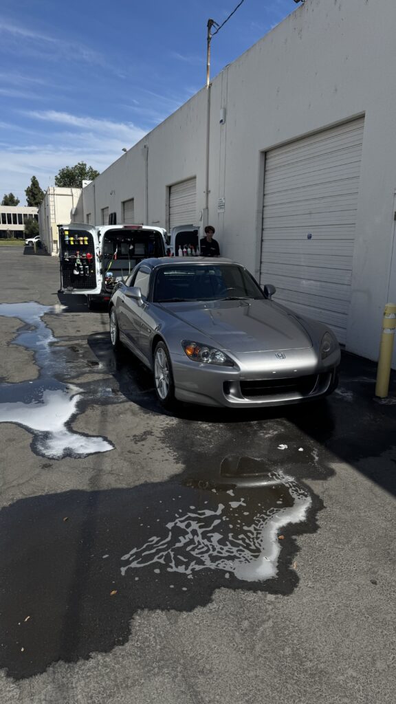 Silver roadster parked in a driveway after a wash and seal