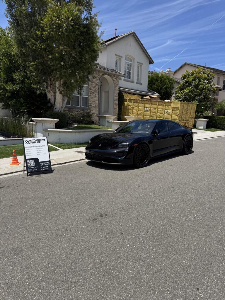 Black sedan parked in a residential driveway after a full detail