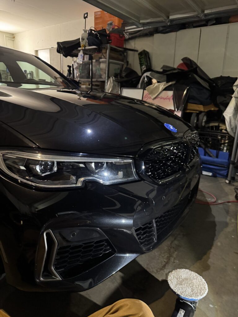 Front end of a black BMW M340i during a machine paint correction